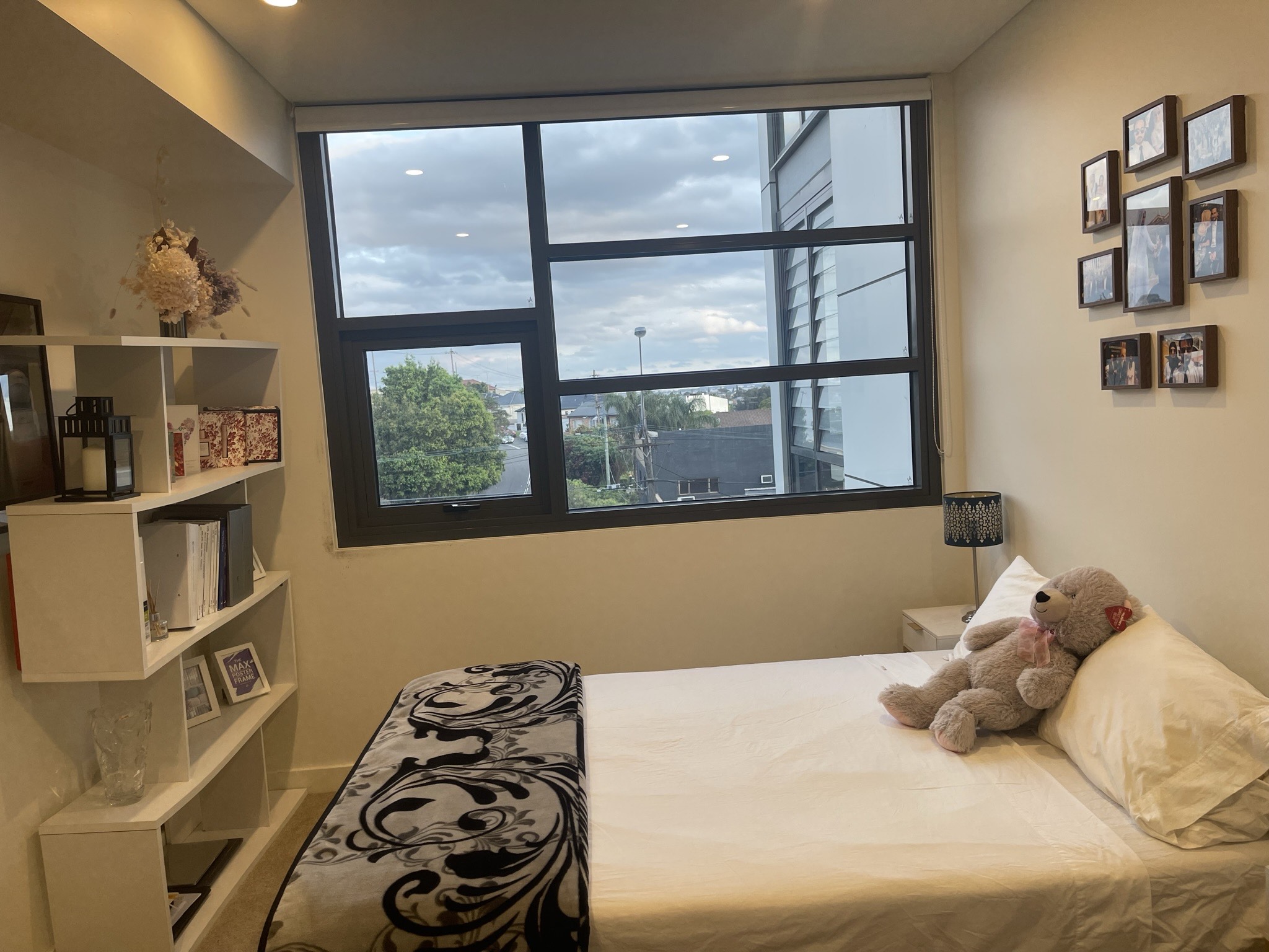 A teddy bear on top of a well-made bed in a bedroom