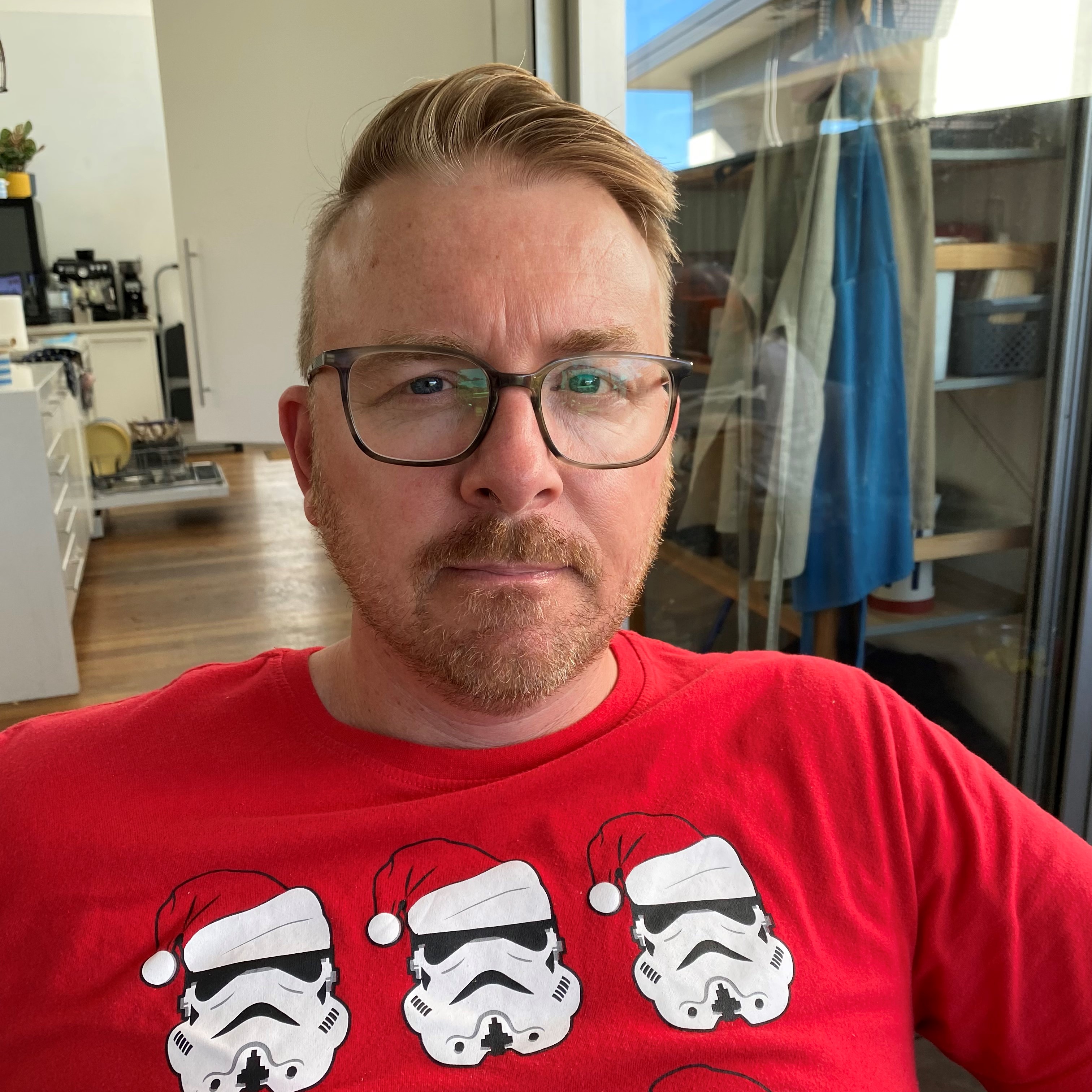 Richard, image of a white man with beard, blue eyes and glasses wearing a red tshirt